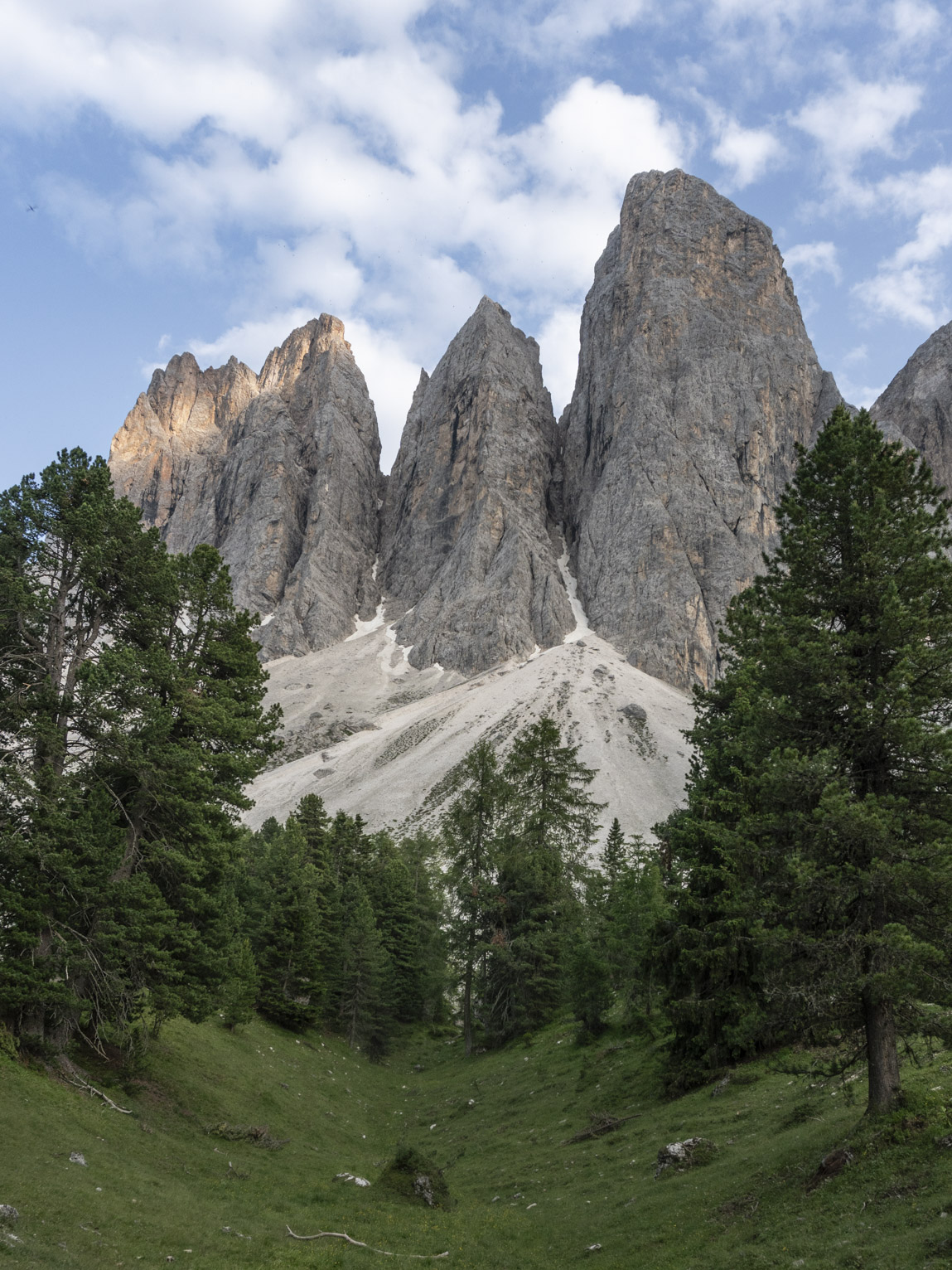 Under four pinacle-like mountains a little dip between conifers, perhaps carved by glaciers?